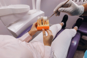 Patient in chair holding a dental implant model with thew doctor giving information