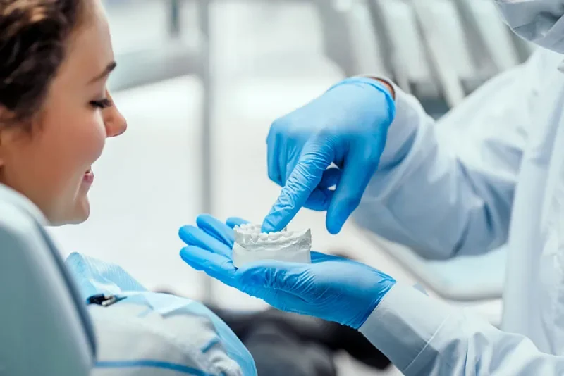 adentist showing an implant patient a dental implant model