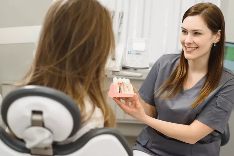dental-assistant-showing-off-dental-implant-model